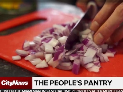 A knife dicing onions on a cutting board.